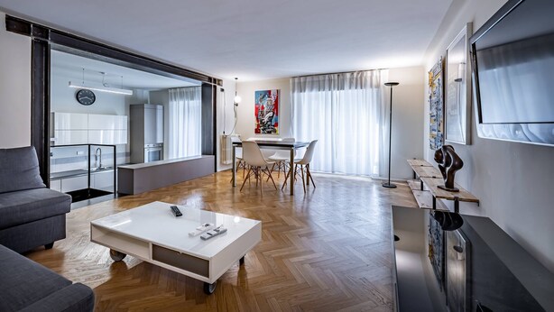 A modern living room with a white sofa, a coffee table, and a dining area with a table and chairs.