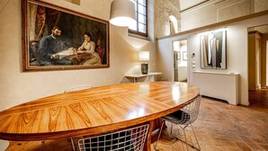 Un coin repas avec une table en bois, des chaises, un tableau et une lampe.