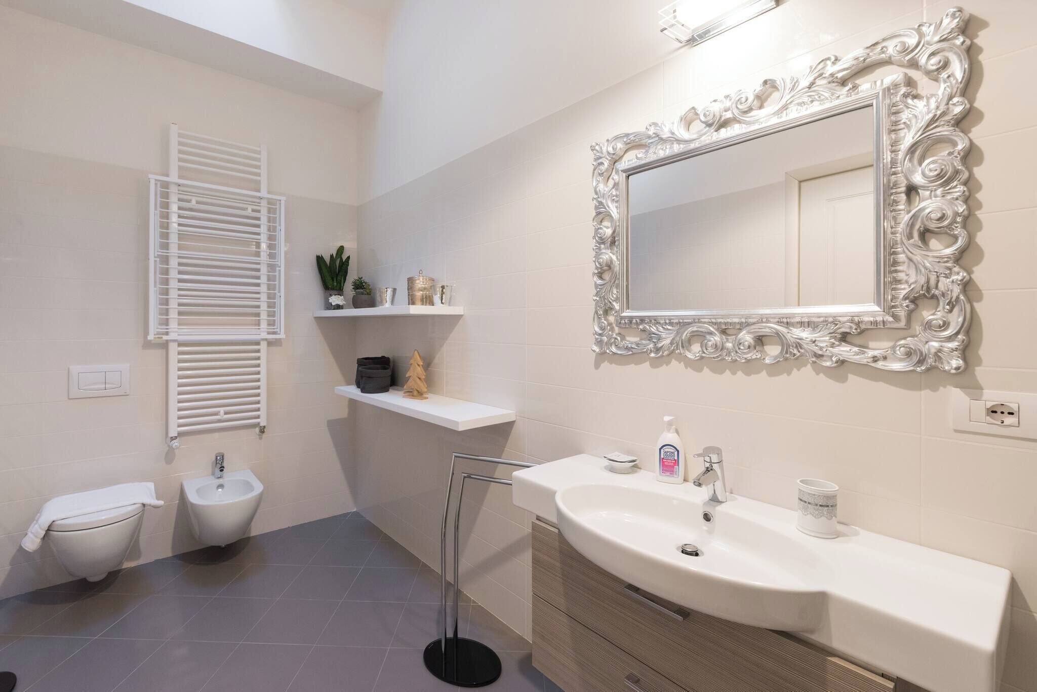 A modern bathroom with a bidet, a sink with a mirror, and a towel rack.