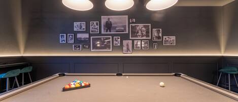 Ein Billardtisch mit Spielball und Billardkugeln, umgeben von blauen Barhocker.
