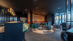 A modern lounge area with seating, a bar, and a bookshelf. - JustStay München Hotel & Apartments (Vaterstetten)