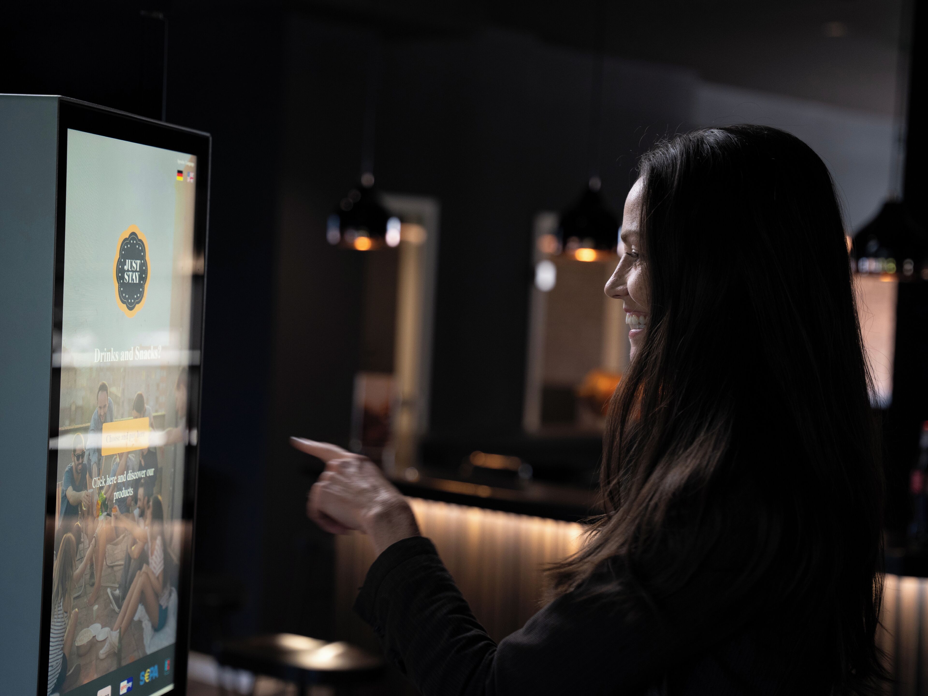 A person interacting with a digital kiosk in a dimly lit indoor setting.