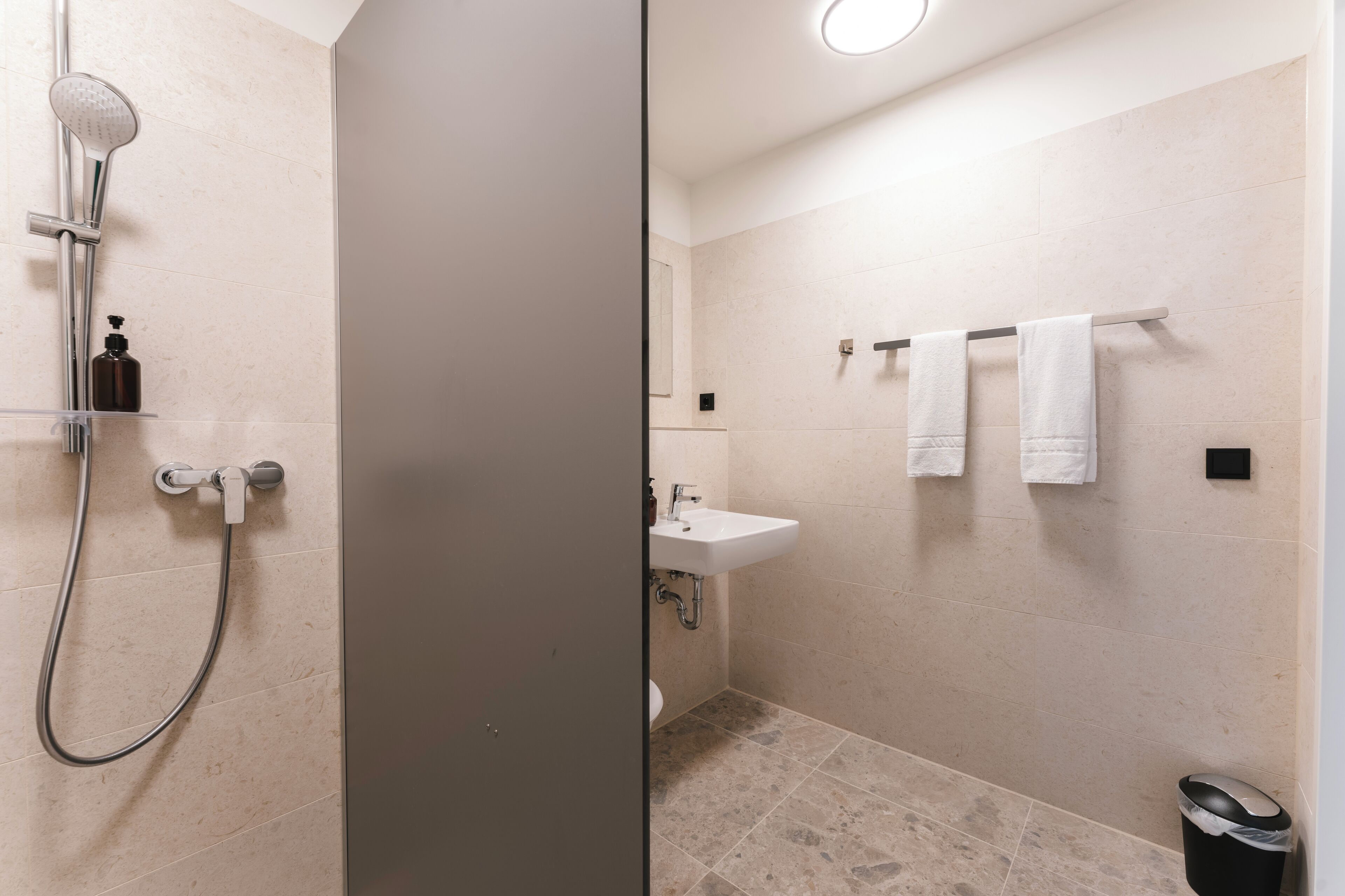 A modern bathroom with a shower, sink, and toilet.