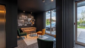 A modern lounge area with a sofa, chairs, and artwork on the wall. - JustStay München Hotel & Apartments (Vaterstetten)