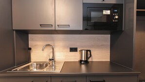 A modern kitchen with stainless steel appliances, a double sink, and wooden backsplash. - JustStay München Hotel & Apartments (Vaterstetten)