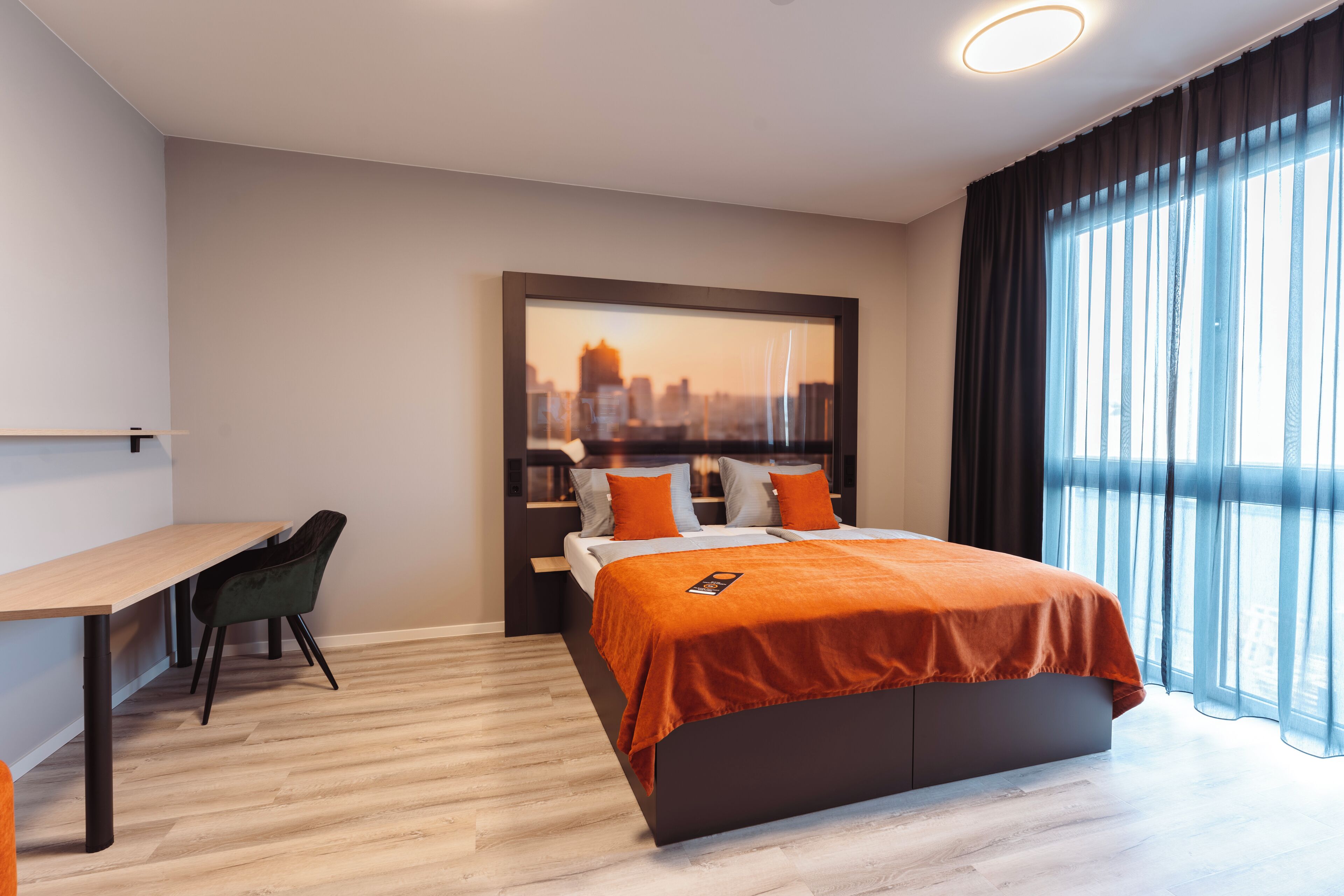 A modern hotel room with a bed, a desk, and a chair.