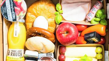 A variety of food items including bread, cheese, apples, tomatoes, and a bottle of orange juice.