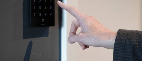 A hand pointing at a digital keypad on a door.