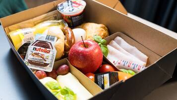 Une boîte contenant divers produits alimentaires, notamment une barre de Nutella, des pommes et un pot de yaourt.