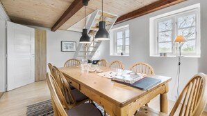 A dining area with a wooden table, six chairs, pendant lights, a ladder, and a window with a view. - 2 bedroom beautiful apartment in Kolind (Kolind)
