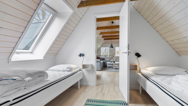 A modern attic bedroom with two beds, a skylight, and a view of the adjacent living area. - 2 bedroom beautiful apartment in Kolind (Kolind)