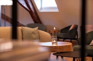 Una habitación acogedora con una mesa redonda de madera, una vela encendida y un sofá con cojines.