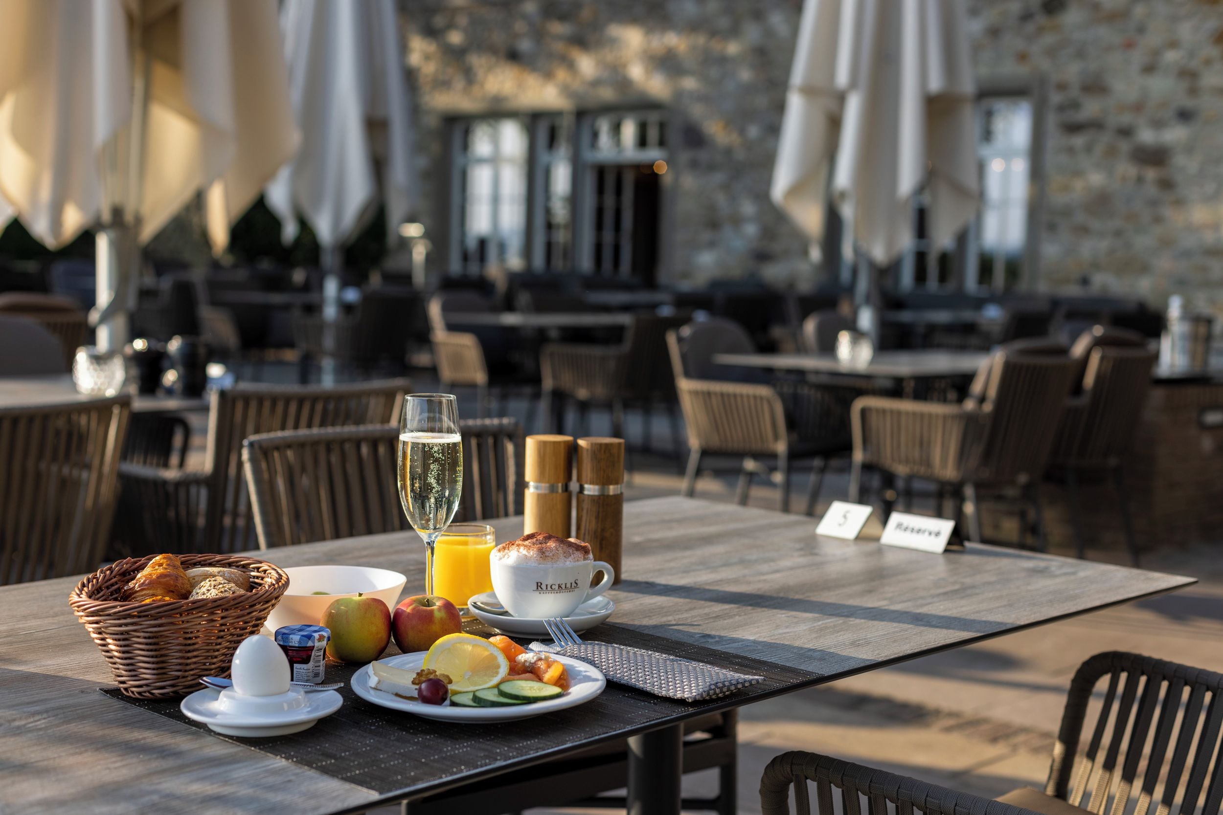 Un espace extérieur aménagé pour les repas, avec des tables, des chaises et des parasols.
