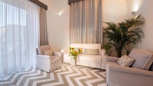 A modern living room with a sofa, two armchairs, a coffee table with a vase of flowers, and a large plant. - Suite Agave close to the centre of Sorrento (Sant´Agnello)