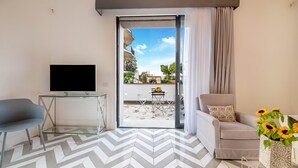 A modern living room with a TV, a sofa, a chair, and a dining table. - Suite Agave close to the centre of Sorrento (Sant´Agnello)