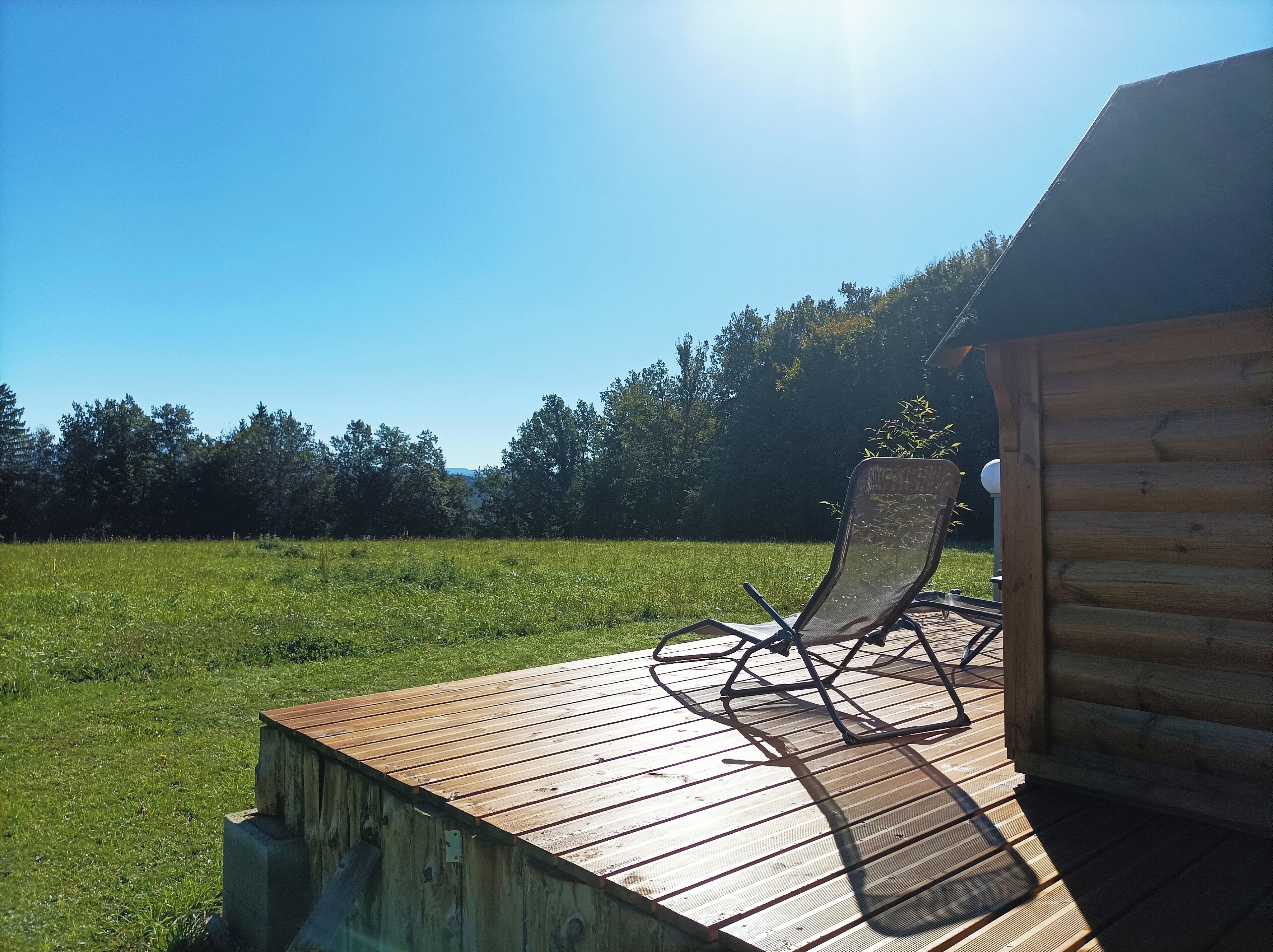 A wooden deck with a chair and a small wooden structure.