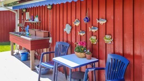 A patio with a red wall, blue chairs, a table, and a small bar area with a sink and potted plants. - Cozy home in Strömstad with WiFi (Strömstad)