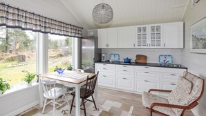 A kitchen with white cabinets, a dining table with chairs, a coffee maker, and a view of the outdoors. - Cozy home in Strömstad with WiFi (Strömstad)