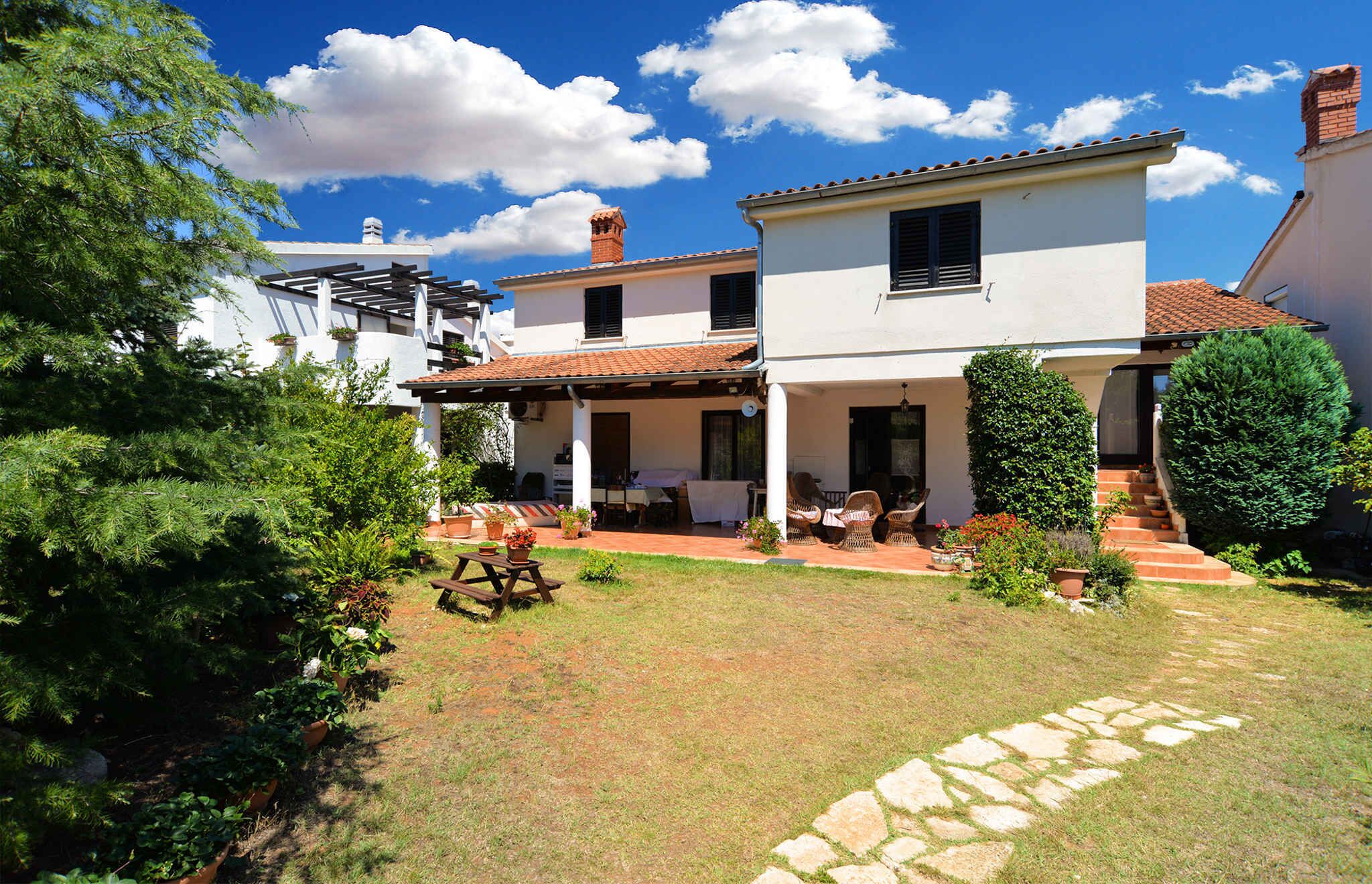 A two-story house with a patio, outdoor seating, and a garden.