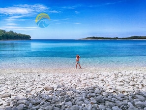 A beach with pebbles and a clear blue sea.
