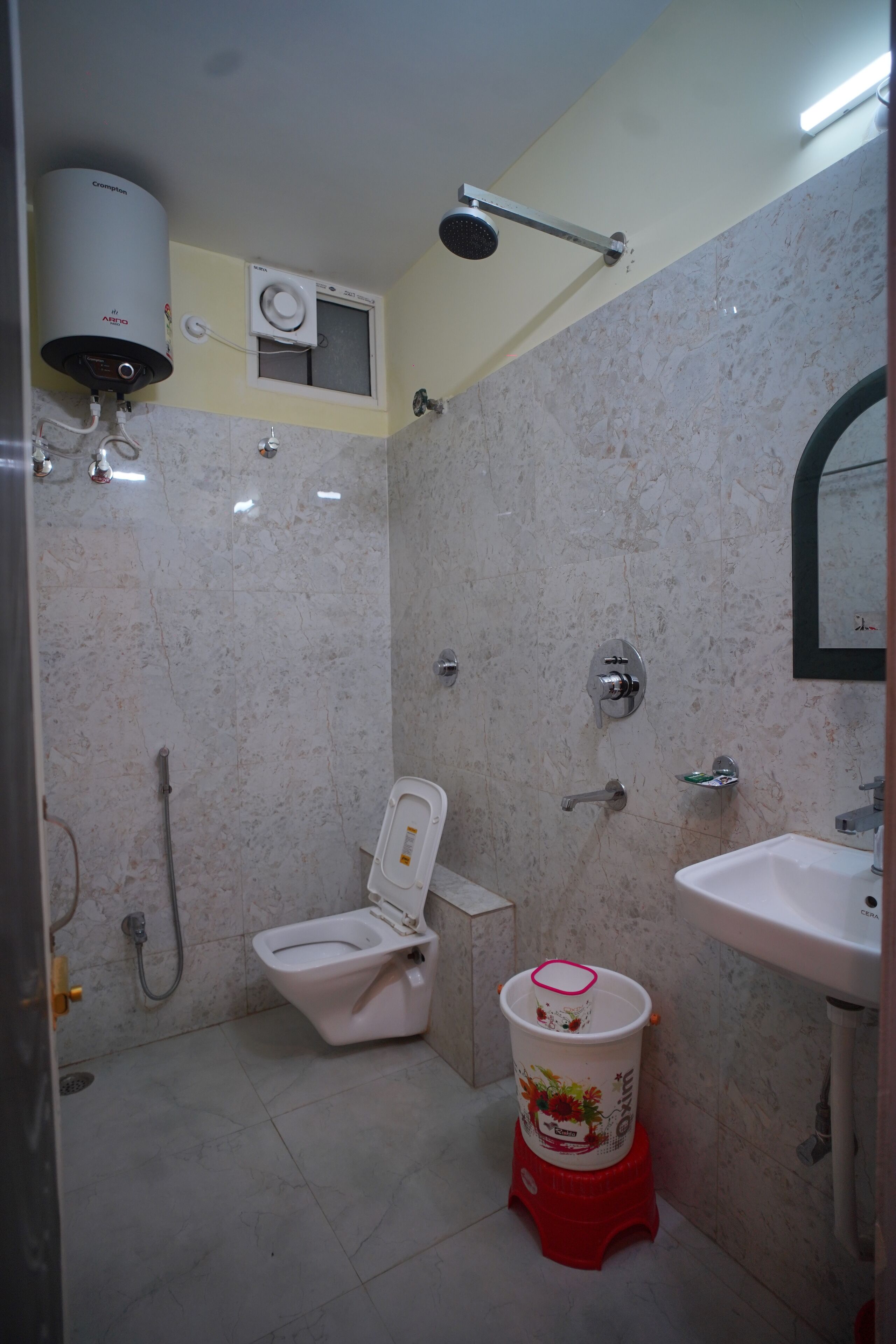 A bathroom with a toilet, sink, shower, and a water heater.
