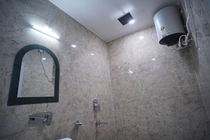 Um banheiro com parede de mármore, espelho fixado na parede, porta-toalhas, chuveiro e aquecedor de parede.