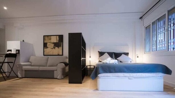 A modern bedroom with a bed, a sofa, and a desk with a chair. - Barcelona - Loft Parc Güell (Barcelona)