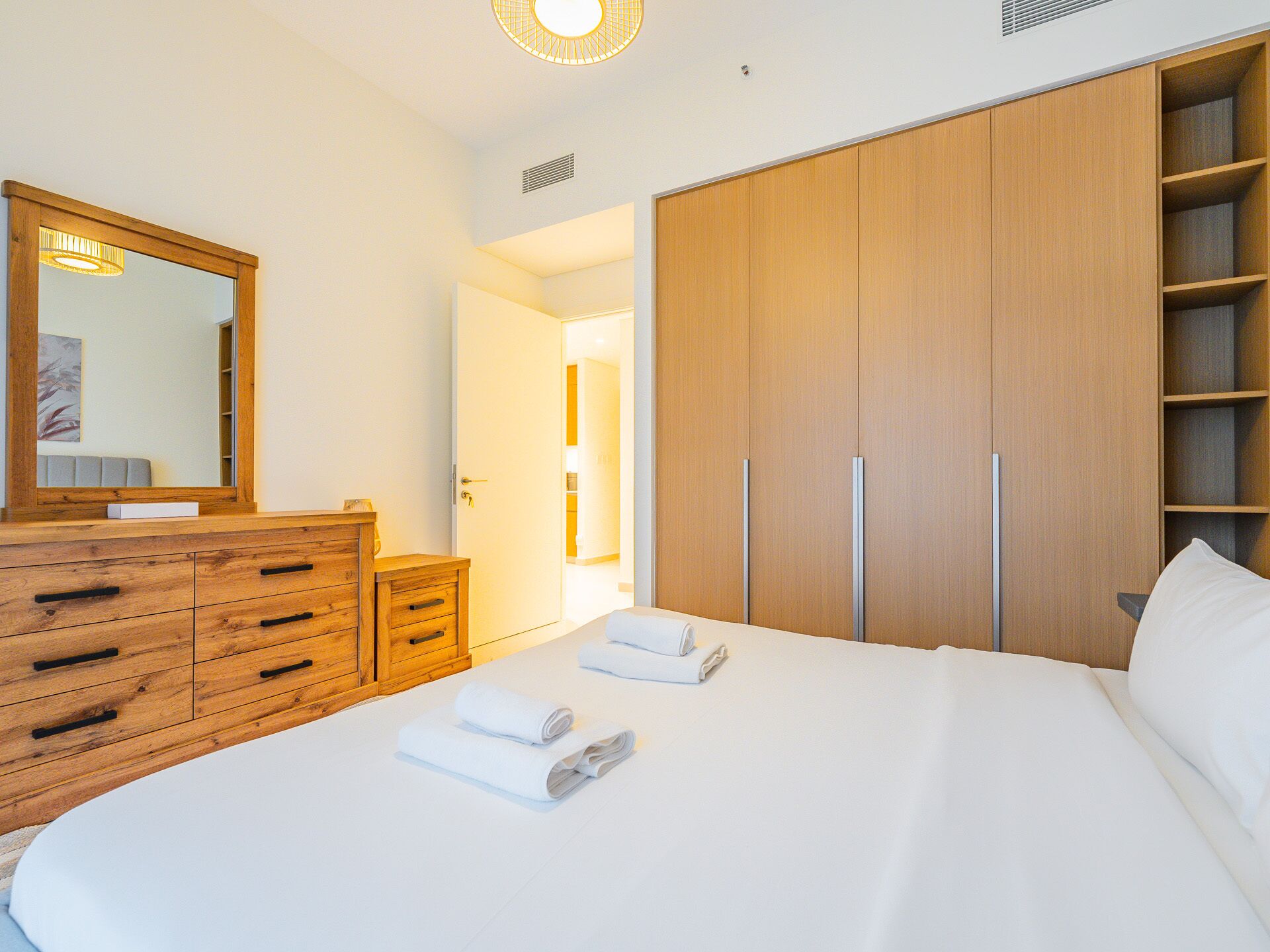 Habitación de hotel con una cama grande, armario de madera y un espejo.