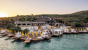 Un hôtel situé au bord de l’eau, doté d’espaces extérieurs aménagés, d’une piscine et d’un bâtiment à la structure circulaire.