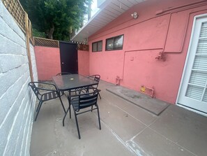 A patio with a table and chairs, a door, and a garage door. - Marilyn Suite · Private Yard (Palm Springs)