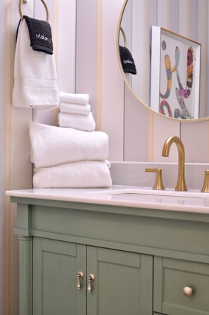 A bathroom with a green vanity, a gold faucet, and a framed artwork on the wall. - Private 9-Suite Hotel · Pool · Hot Tub · Sleeps 22 (Palm Springs)