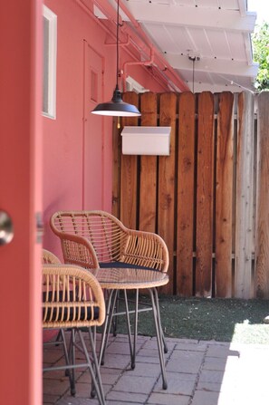 Een terras met rieten stoelen en een hanglamp.