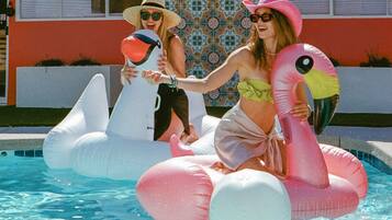 Duas pessoas em uma piscina com boias de flamingo.