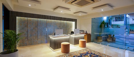 A modern reception area with a glass partition, a reception desk, and a patterned wall.