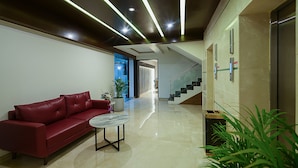 A modern lobby with a red leather sofa, a marble coffee table, and a staircase leading to an upper level. - Grand Continent Malleshwaram A Sarovar Portico Affiliate Hotel (Bengaluru)