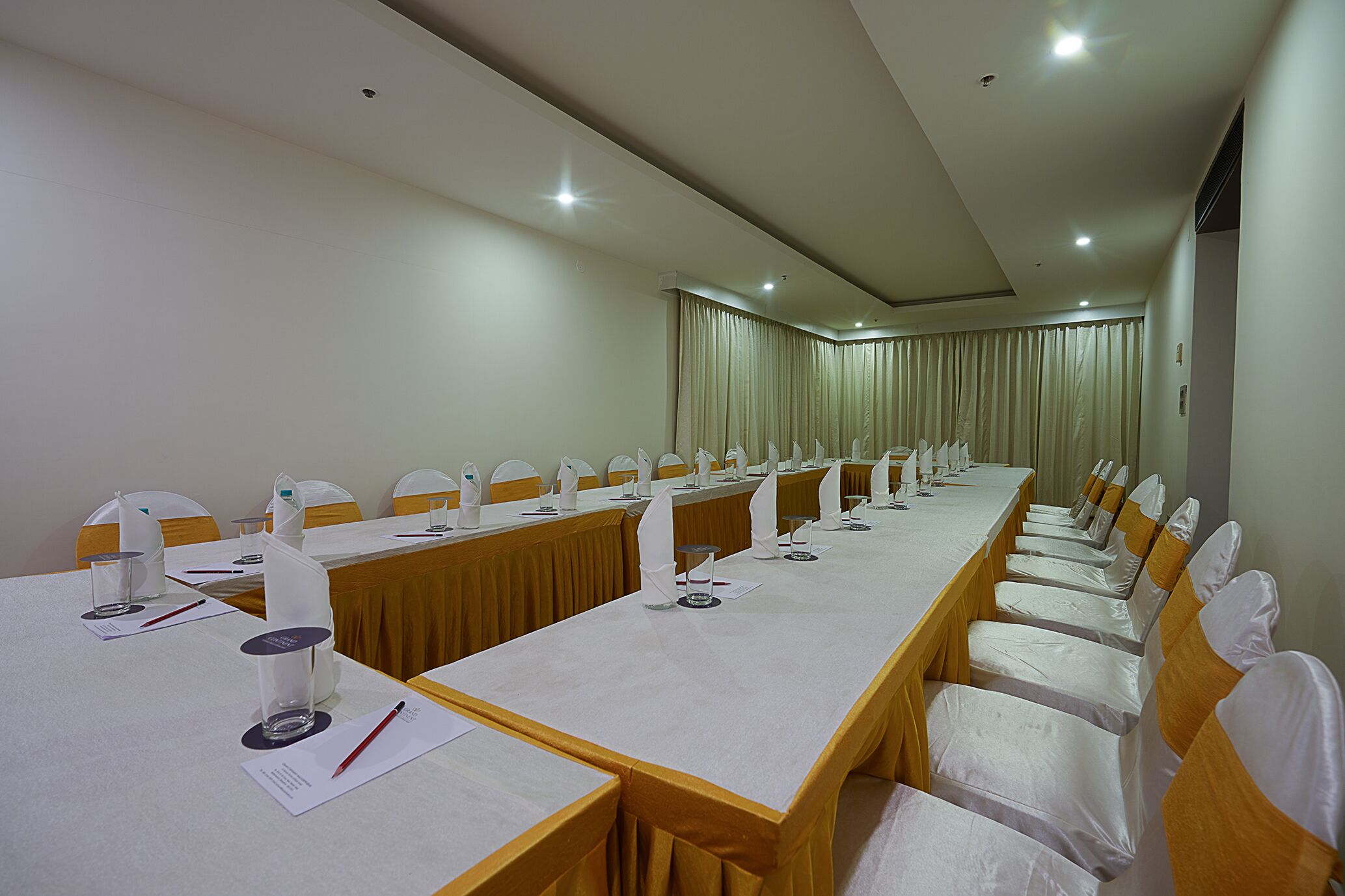 A conference room with a long table, chairs, and a curtain backdrop.