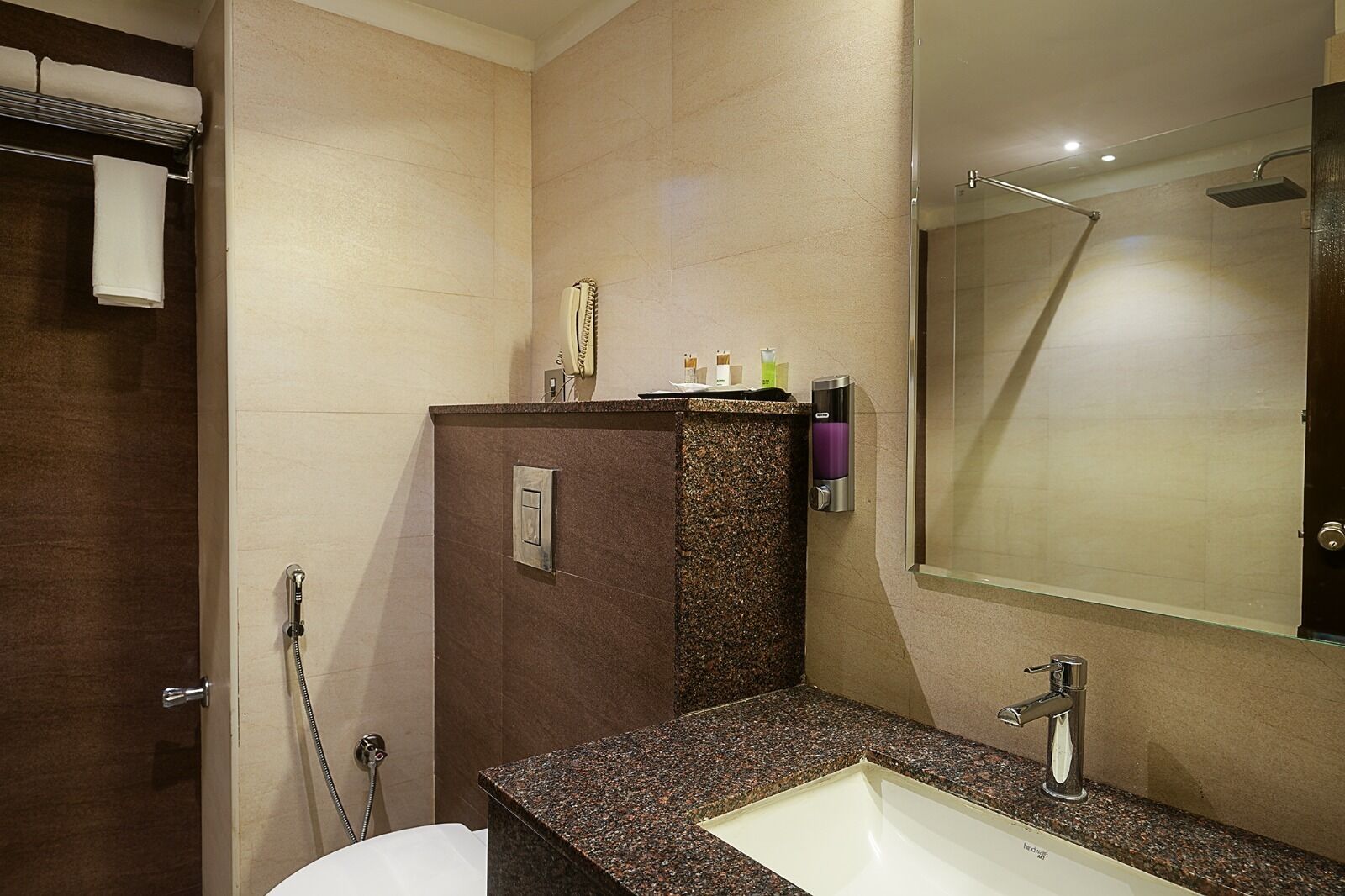 Een moderne badkamer met een wastafel van graniet, een spiegel en een douchehoek.