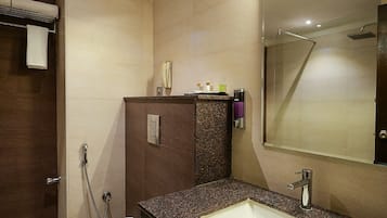 Un bagno moderno con lavabo in granito, specchio e zona doccia.
