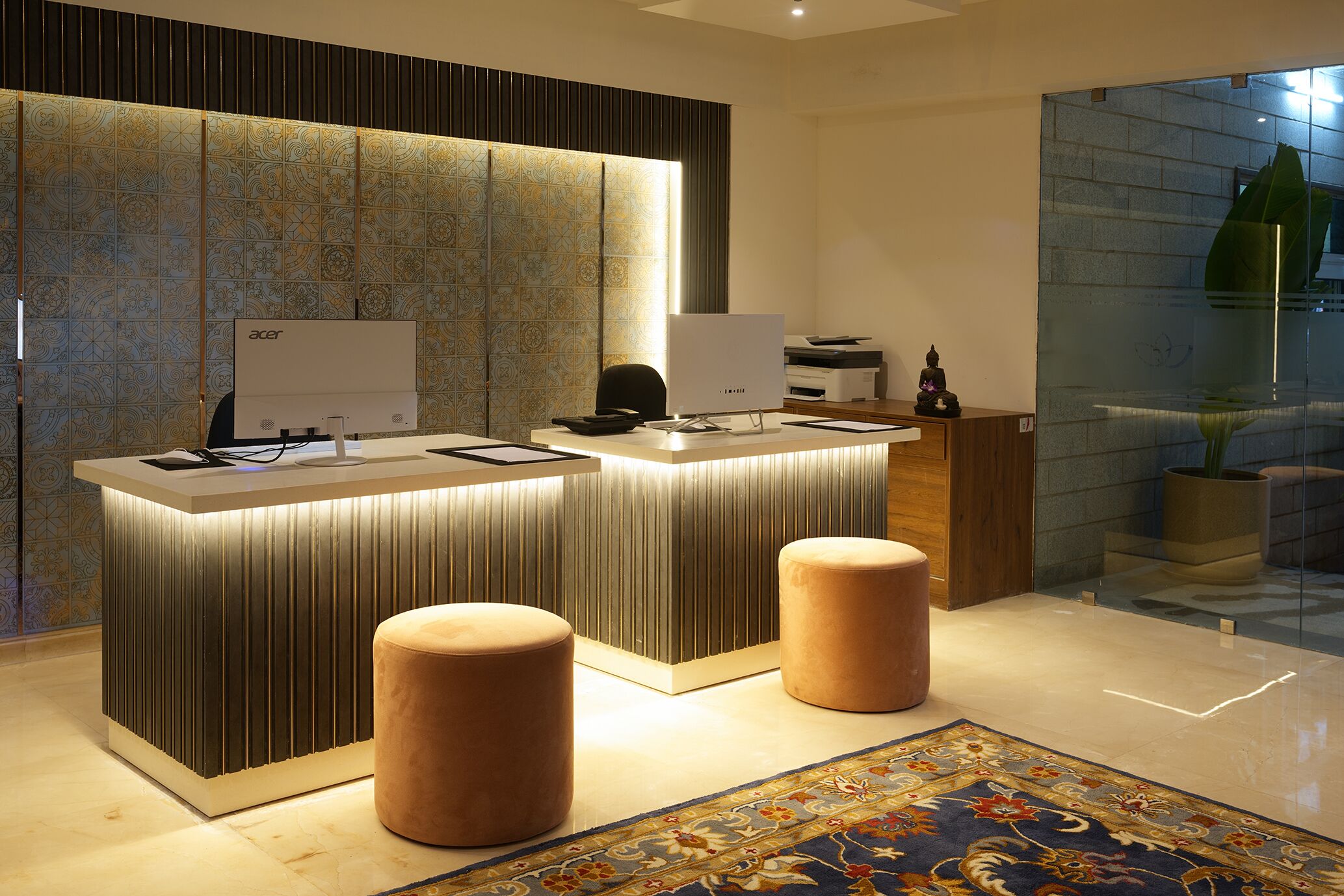 A modern reception desk with two monitors, a patterned wall, and a decorative rug.
