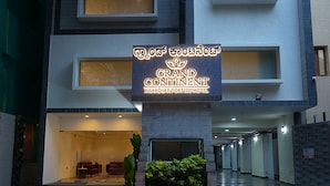 The exterior of the Grand Continental hotel with a sign in a foreign language, a reception area with seating, and a plant in the foreground. - Grand Continent Malleshwaram A Sarovar Portico Affiliate Hotel (Bengaluru)