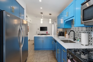 A modern kitchen with blue cabinets, a stainless steel refrigerator, a black stove, and a white countertop. - Bowie Suite · Palm Springs Pool, Hot Tub, Kitchen (Palm Springs)