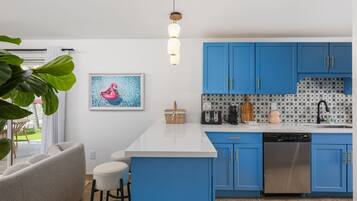 A modern kitchen with blue cabinets, a white countertop, and a stainless steel dishwasher.