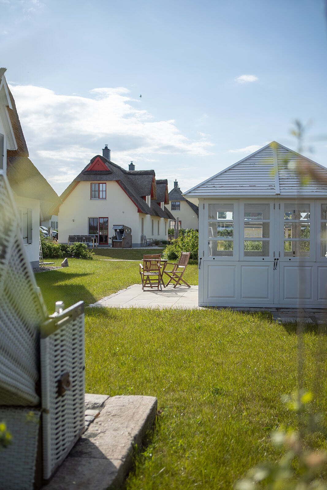 A residential area with houses, a gazebo, and a lawn with chairs.