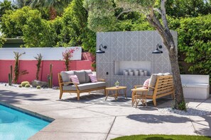 An outdoor patio with a pool, a patterned wall, and seating arrangements. - The Barbie Suite · Adults-Only Palm Springs Pool (Palm Springs)