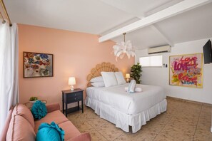 Une chambre à coucher comprenant un lit, une table de chevet, une commode, un canapé et un mur orné d’un tableau.