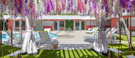 A poolside area with white lounge chairs, a small pool, and hanging floral decorations.