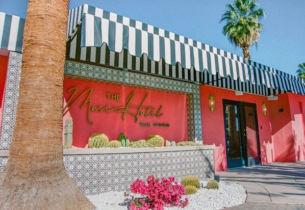 Un bâtiment à la façade rouge, doté d’un auvent à carreaux et d’une enseigne indiquant : « The Moss Hotel Palm Springs ».