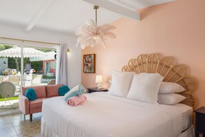 A bedroom with a bed, a nightstand, a lamp, a chair, and a view of the outdoors. - The Barbie Suite · Adults-Only Palm Springs Pool (Palm Springs)
