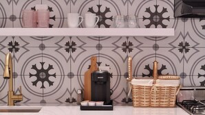 A kitchen with a patterned backsplash, a coffee maker, and a basket on the counter.