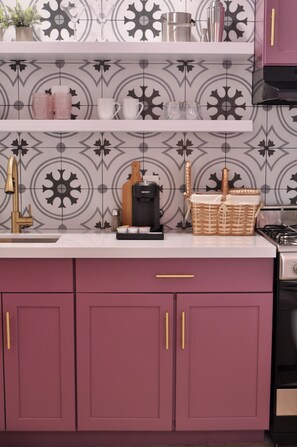 A kitchen with a patterned backsplash, a coffee maker, and a basket on the counter. - Brigitte Suite · Dog-Friendly Yard, Palm Springs (Palm Springs)